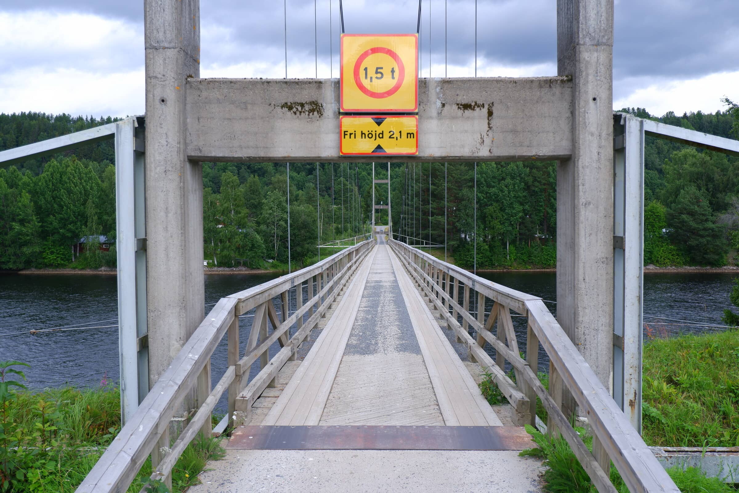An old wooden bridge. Picture taken straight thru the pylons. There's a sign above the road telling people that it can handle less than 1.5 tonnes.