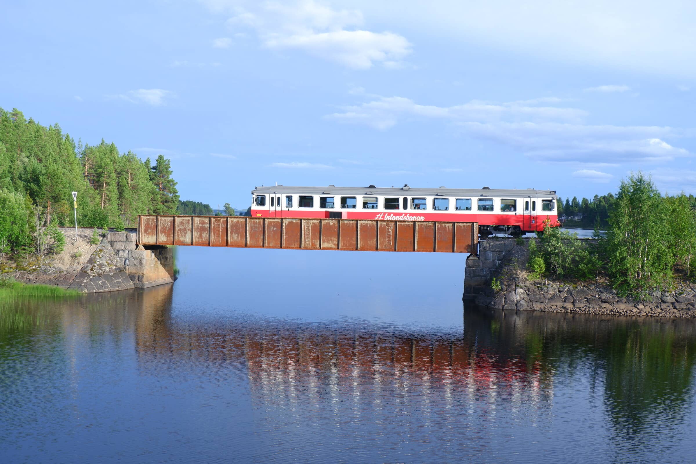 A two-wagon passenger train going over a bridge.